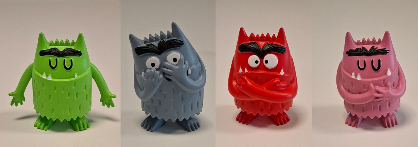 Vier bunte Monsterfiguren in Grün, Blau, Rot und Pink mit unterschiedlichen Gesichtsausdrücken.