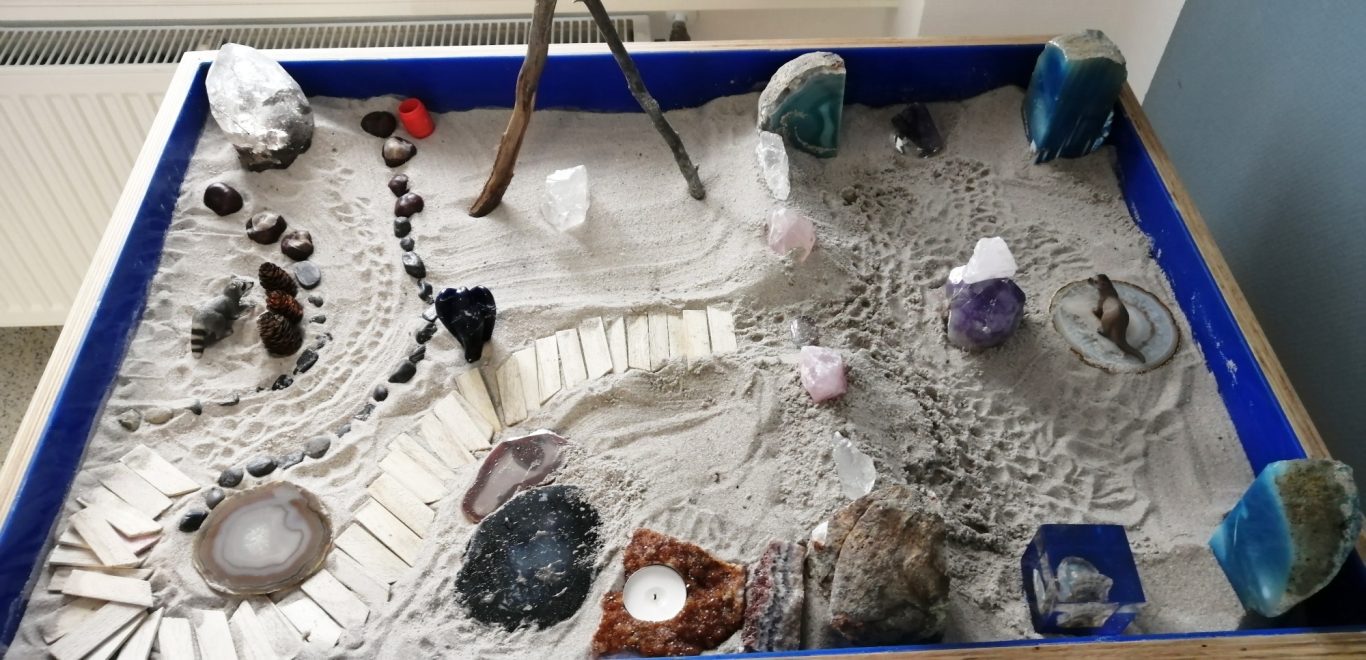 Sandkasten mit verschiedenen Mineralien und Steinen angeordnet.
